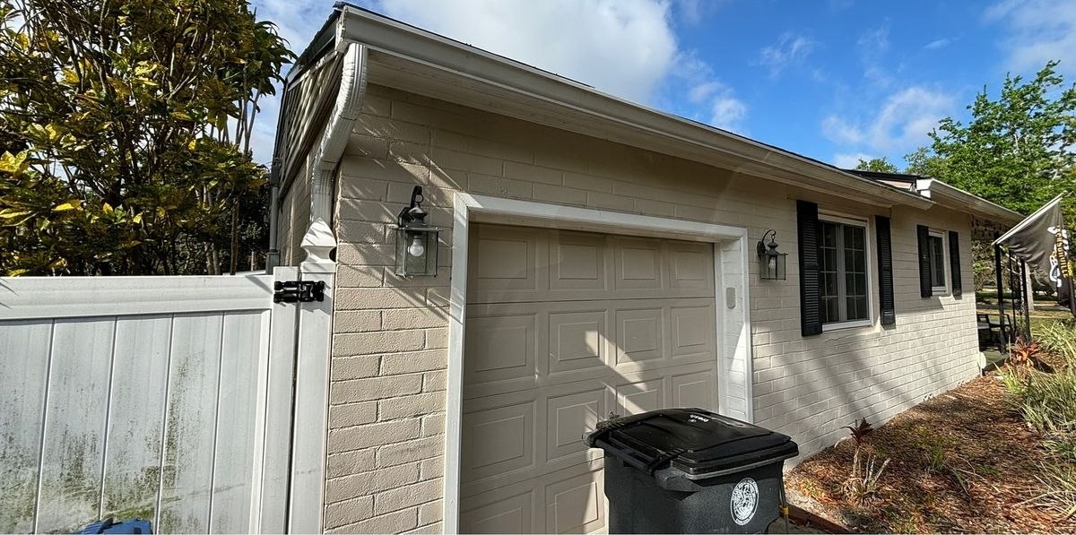Before: beige brick garage, faded door and a stained vinyl fence